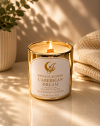 Candle with 'Joha Collections Caribbean Dream' label on a reflective surface with a plant and textured fabric in the background.