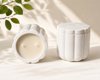 Two white ceramic containers with a candle on a light background
