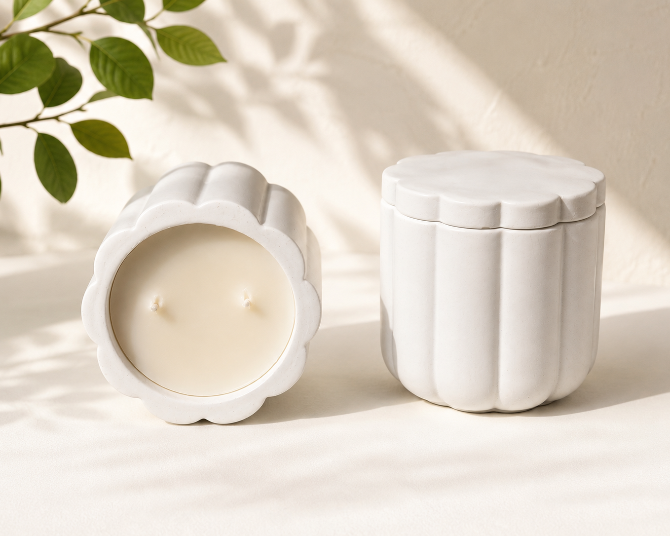 Two white ceramic containers with a candle on a light background