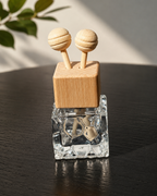Clear glass diffuser with wooden top and two round knobs on a dark surface.