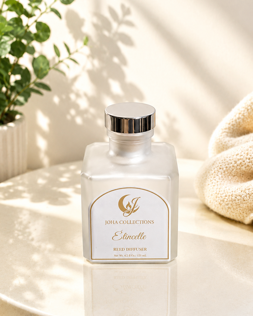 White diffuser bottle with gold label on a light surface with a plant in the background