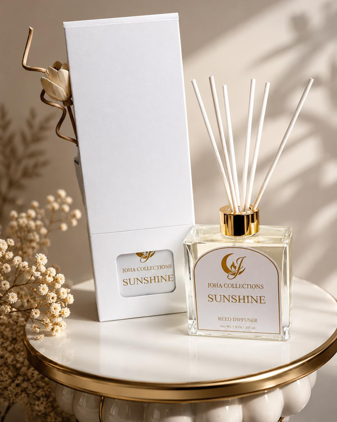 Reed diffuser labeled 'Sunshine' by John Collections on a marble surface with a white box in the background.