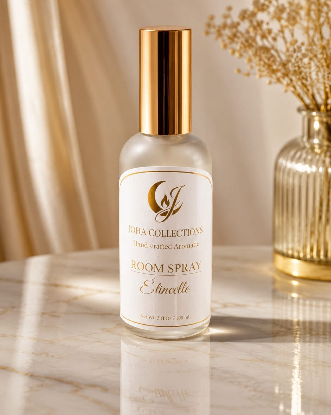 Room spray bottle labeled 'Joho Collection' on a reflective surface with a decorative vase in the background. Main image