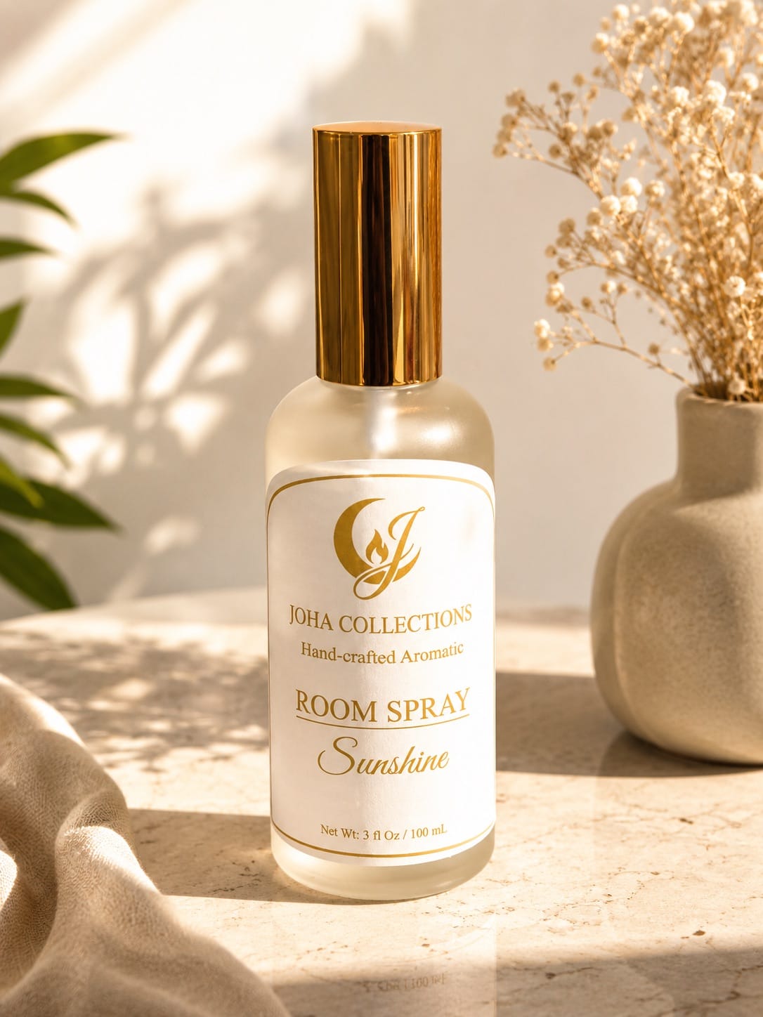 Room spray bottle labeled 'Joha Collections' on a surface with decorative elements.