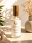 Room spray bottle labeled 'Joha Collections' on a surface with decorative elements.