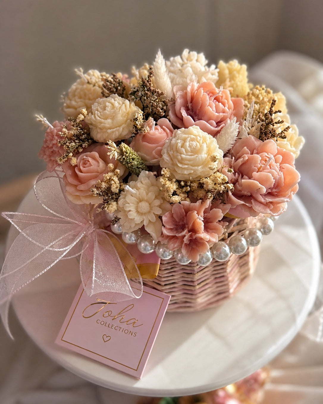 Decorative flower arrangement in a basket with a pink bow and tag on a white surface. Main image
