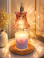 Decorative candle with a glass shade on a wooden base, surrounded by soft lighting.