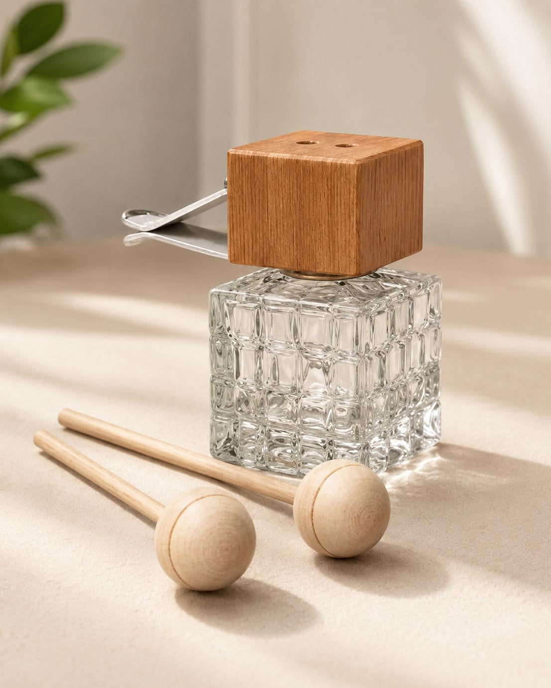 Clear glass diffuser with wooden top and two wooden rollers on a beige surface.