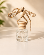 Clear glass diffuser with wooden top and rope on a light background